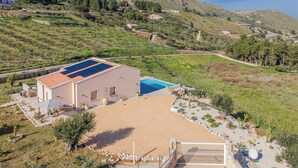 Una casa moderna amb piscina, envoltada d'un jardí ben cuidat i amb un paisatge de muntanyes al fons.