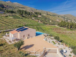 Ein modernes Haus mit Swimmingpool, umgeben von einem angelegten Garten und einer Bergkulisse.