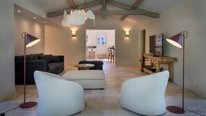 A modern living room with a sofa, ottoman, and two armchairs, a dining area with a table and chairs, and a kitchen in the background. - Renovated dovecote near the city of Albi (Marssac-sur-Tarn)