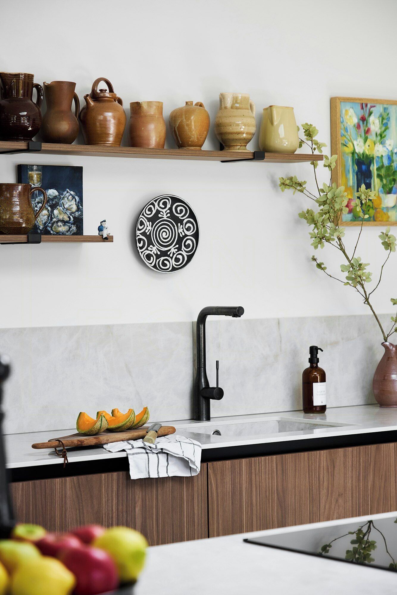 A kitchen with a modern faucet, a wooden countertop, and various kitchenware on shelves.