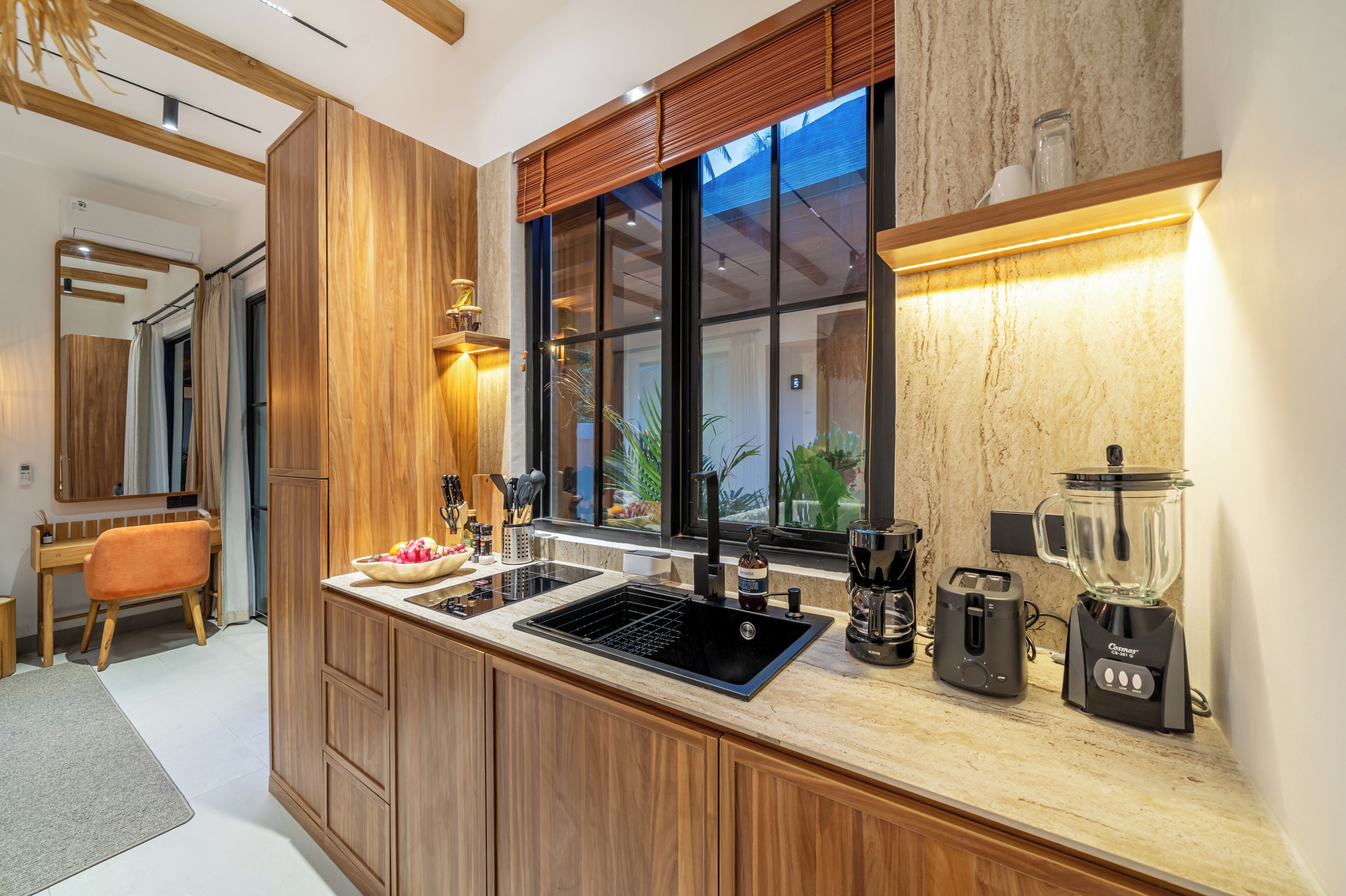 Une cuisine moderne avec des meubles en bois, un évier noir, une machine à café et un mixeur.