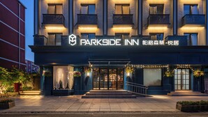 A multi-story hotel with a prominent entrance, illuminated signage, and a well-lit facade.