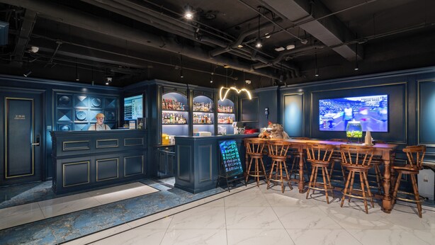 A bar area with a high counter, stools, and a television screen.