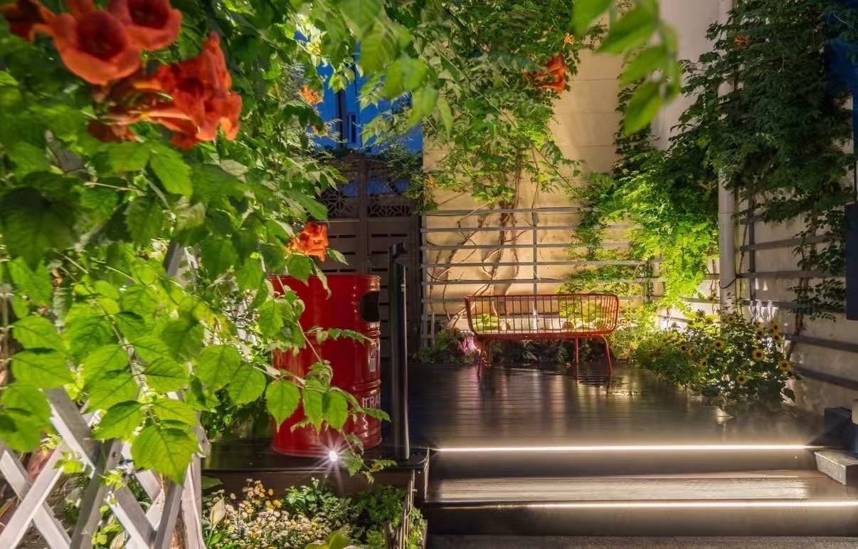 A staircase leading to a rooftop garden with potted plants and a metal chair.