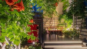 A staircase leading to a rooftop garden with potted plants and a metal chair.