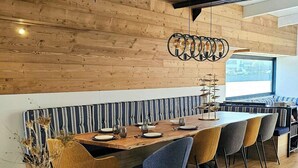 Een moderne keuken met houten wanden, een marmeren aanrecht en een eethoek met gestreepte zitplaatsen.