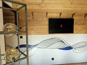 Una habitación con paneles de madera, un televisor montado en la pared y una pieza de arte decorativa.