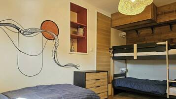 Een kamer met stapelbedden, een houten plafond, een kunstwerk aan de muur en een hanglamp.