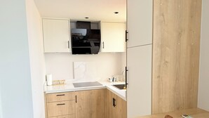 Una cocina compacta con armarios de madera, una encimera blanca y un microondas integrado.