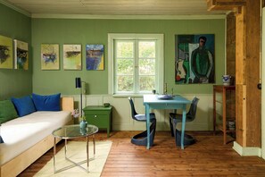 Une pièce comprenant un lit, une table avec des chaises, une fenêtre et des œuvres d’art accrochées aux murs.