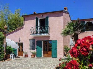 A pink building with a balcony, green shutters, and potted plants. - Ground floor apartment with sea view near Lucca (Massarosa)
