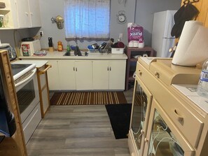 A compact kitchen with white cabinets, a sink, a stove, and a refrigerator. - 3 bedrooms cabin for rent (Sandy Hook)