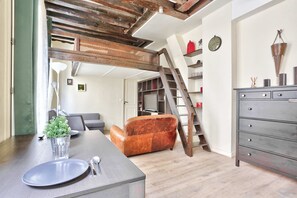 Ein Essbereich mit einem Tisch für zwei Personen, einer Couch, einer Kommode und einer Treppe zu einem weiteren Raum.