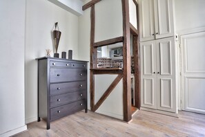 Ein Zimmer mit Holzboden, einer dunklen Kommode mit Schubladen, einer weißen Tür und einem Holzbalkenbau.