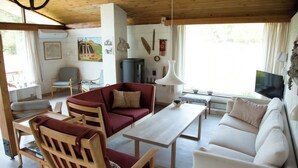 En stue med træloft, sofa, sofabord, fjernsyn og pejs.