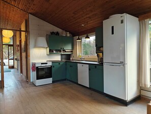 Une cuisine avec des meubles de rangement en bois, un réfrigérateur, un four et un lave-vaisselle.