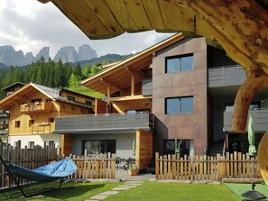 Ein modernes Gebäude mit Holzfassade, Balkonen und Bergblick.