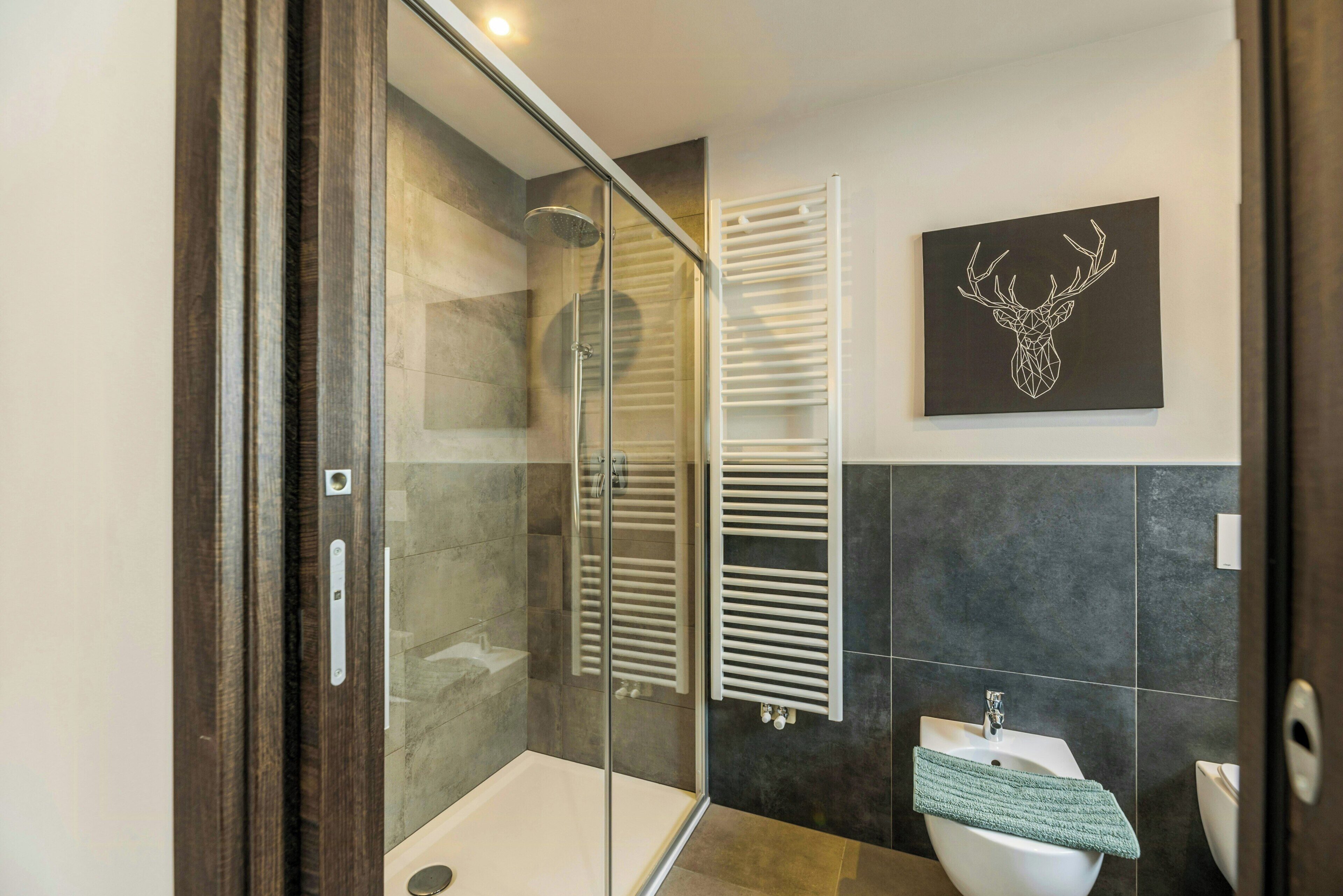 Une salle de bain moderne avec une douche à parois de verre, un lavabo blanc et un porte-serviettes.