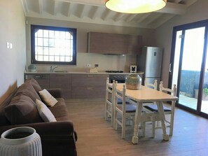 Une cuisine avec une table à manger, des chaises, un canapé et une grande fenêtre.