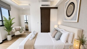 A modern bedroom with a large bed, bedside tables, a potted plant, and a view of the adjacent living area.