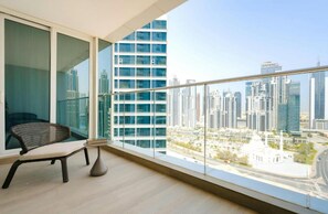 Un balcón con vistas a edificios altos y una silla.