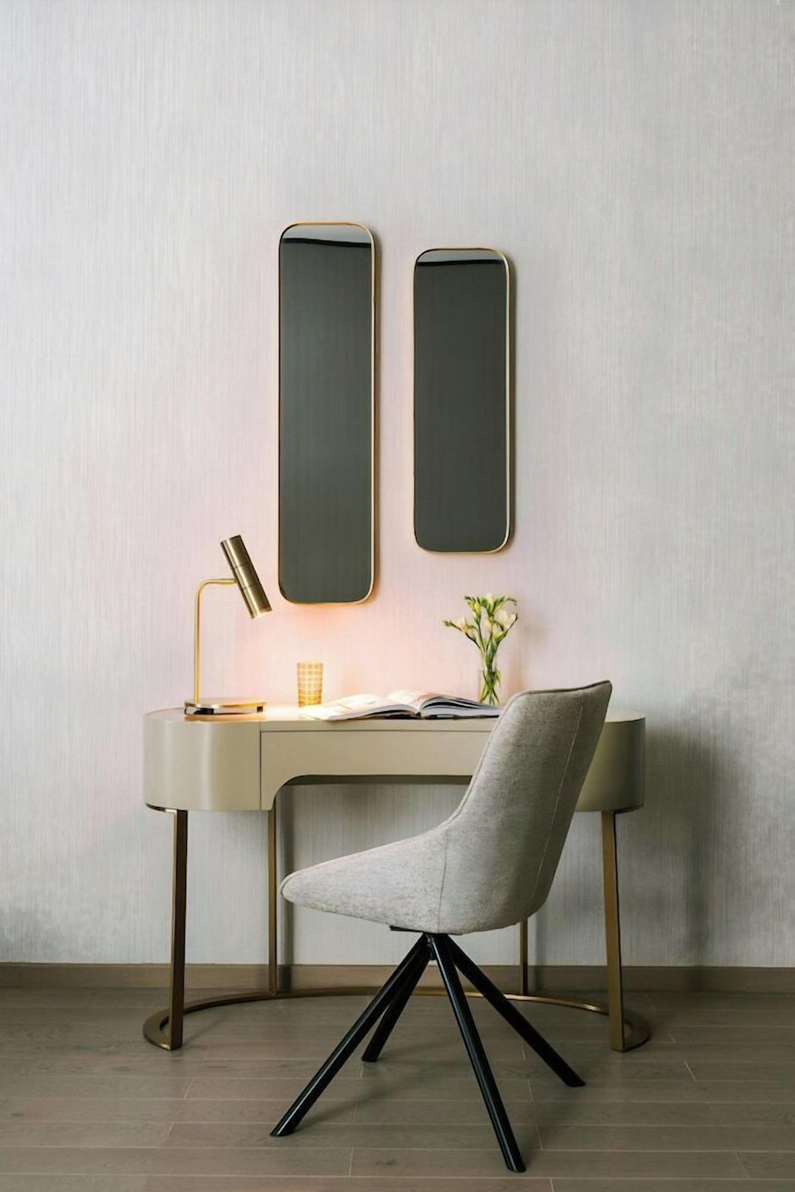 Un bureau moderne, avec une lampe, une chaise et deux miroirs muraux.