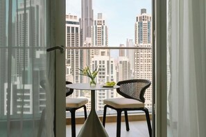 A balcony with a table and chairs, a vase with flowers, and a cityscape view. - Aura Suites Downtown (Dubai)