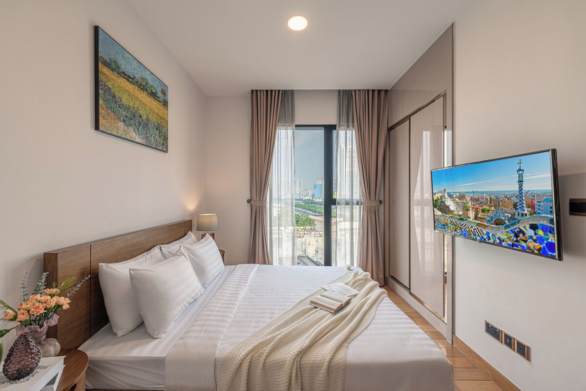 Ein Hotelzimmer mit Bett, Fernseher, einem Gemälde und einem Fenster mit Vorhängen.