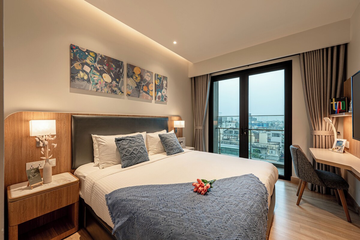Ein modernes Hotelzimmer mit einem großen Bett, einem Schreibtisch und Blick auf die Stadt.