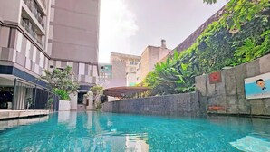 A swimming pool with clear blue water, surrounded by buildings and greenery. - Zenity & D1 Mension Apartment by NIDOVA (Ho Chi Minh City)