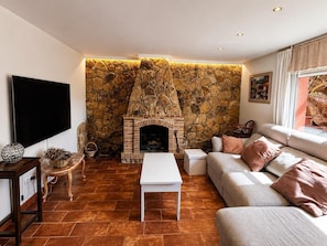 Ein Wohnzimmer mit Kamin aus Stein, einem Flachbildfernseher, einer Couch und einem Couchtisch.