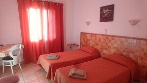 Una habitación con dos camas, un escritorio, una silla y una pequeña mesa.