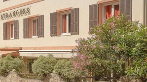 Un hotel con un letrero que dice 'HOTEL DES ETRANGES' y una pared de piedra con follaje al frente.