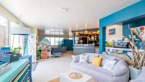 A hotel lobby with a reception desk, seating area, and a counter with a menu. - Atlantic Coast Family Apartment (Biscarrosse)