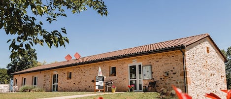 A stone building with a tiled roof, a door, and a small signboard.