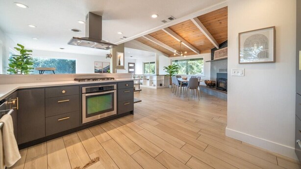 A modern kitchen with a central island, built-in oven, and a dining area with a table and chairs.