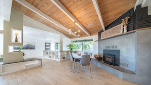 A spacious kitchen with a fireplace, wooden flooring, and a dining area with chairs.