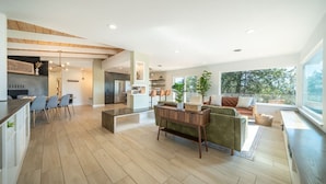 A spacious living area with a dining table, sofas, and a kitchen in the background.
