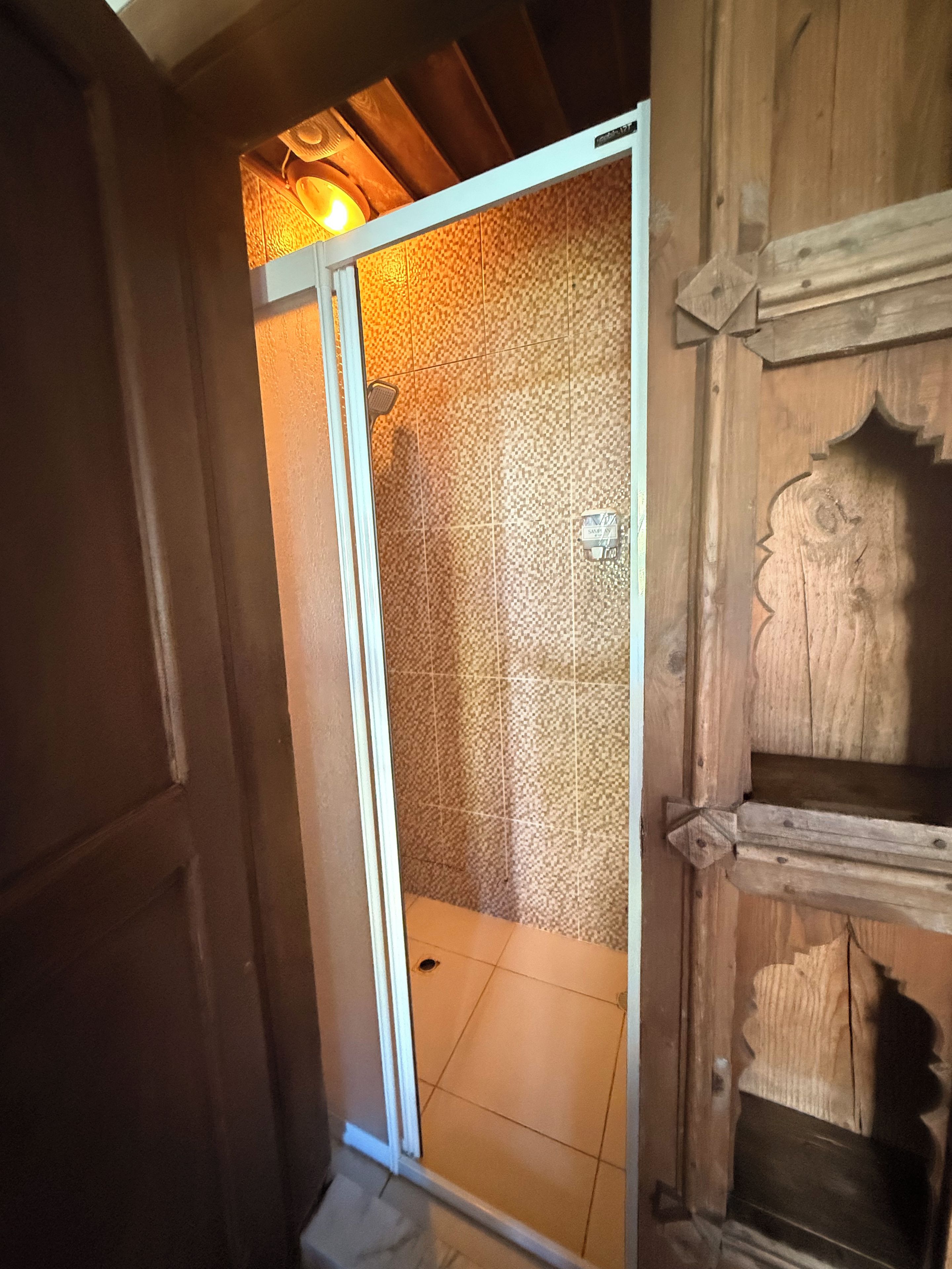 A wooden door with a glass panel leading to a tiled room.