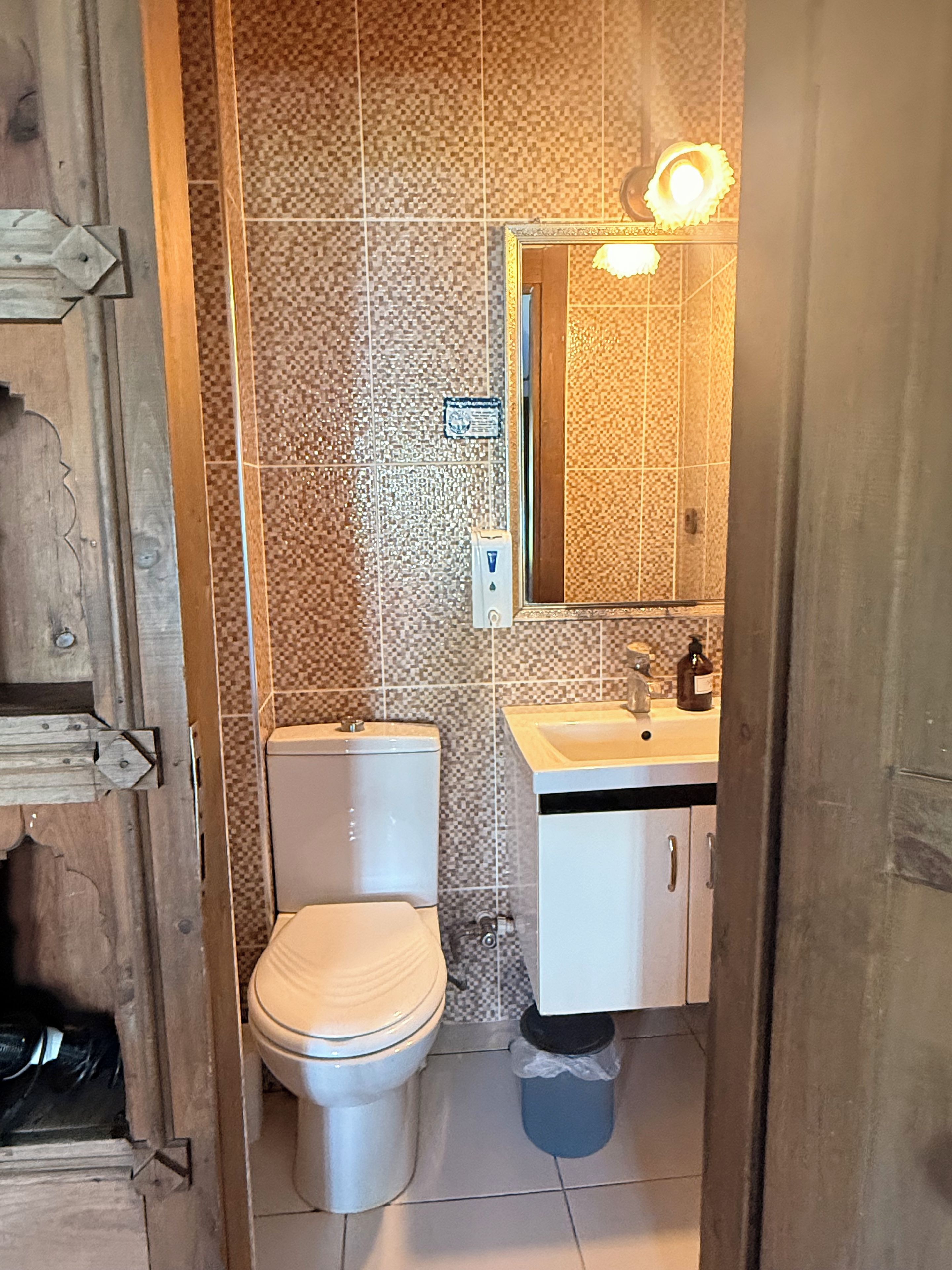 A bathroom with a toilet, sink, and mirror.
