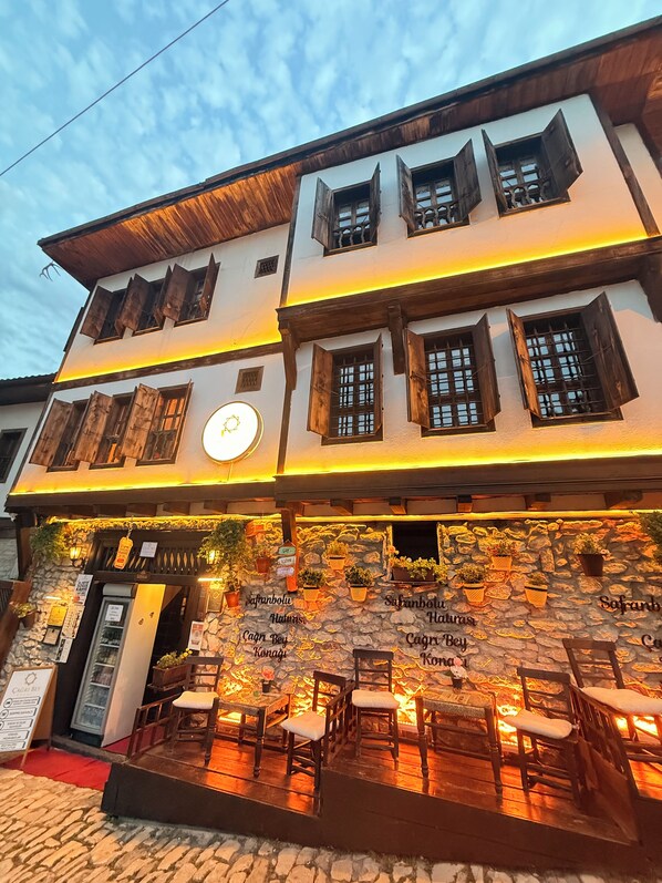 A two-story building with a stone facade, wooden shutters, and outdoor seating area. - çağrı bey konağı  (Safranbolu)