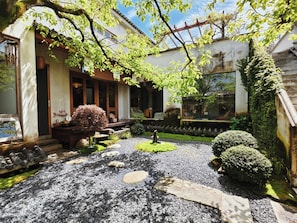 A traditional Japanese-style building with a wooden porch, a koi pond, and a stone pathway.