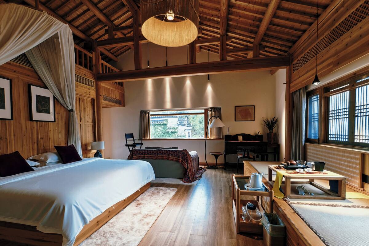 Un dormitorio amplio con una cama grande, un escritorio y vistas al exterior.