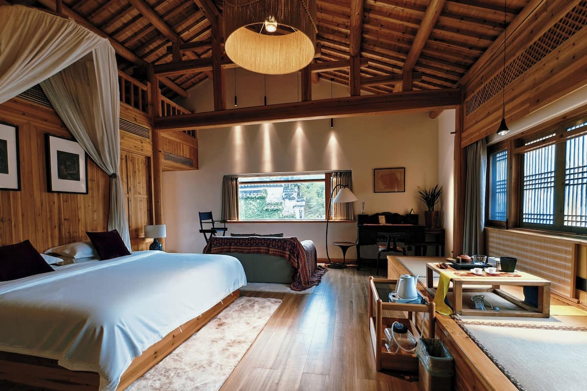 A spacious room with a large bed, a desk, and a view of the outdoors.