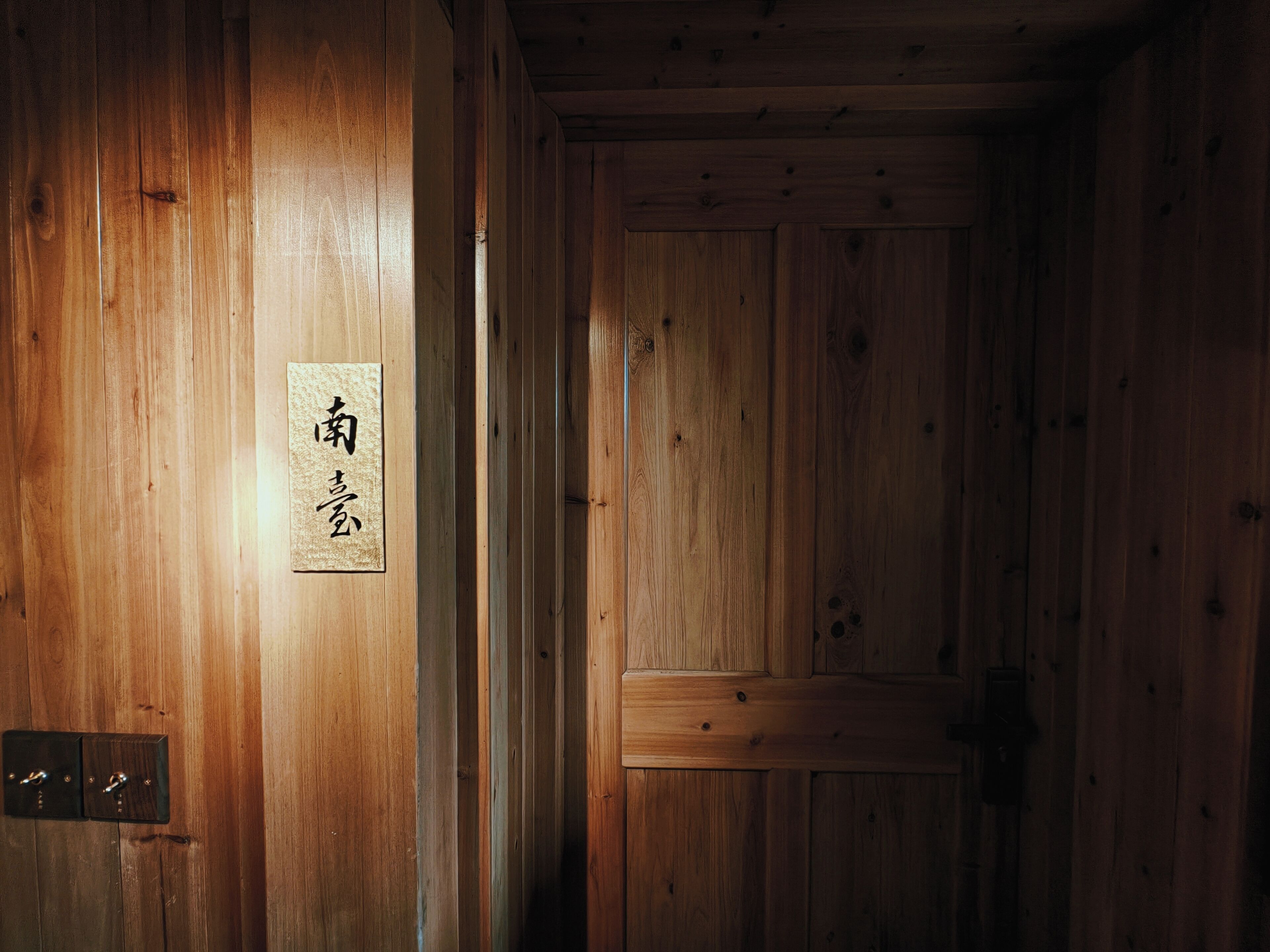 Una puerta de madera con un letrero, una pared de madera y un picaporte.