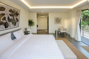 A modern hotel room with a large bed, a desk, a chair, a potted plant, and a view of the outdoors. - VILLA AZURE - 4BR LUXURY VILLA (ตำบลเกาะพะงัน)