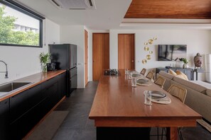 A modern kitchen with a wooden countertop, a built-in oven, and a large dining table set for six. - VILLA AZURE - 4BR LUXURY VILLA (ตำบลเกาะพะงัน)