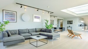 Ein modernes Wohnzimmer mit einem grauen Ecksofa, einem Couchtisch und einem Essbereich mit einem Stuhl.