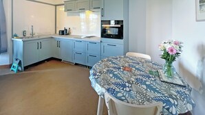 A compact kitchen with light blue cabinets, a sink, and a dining area with a table set for two. - Plover Apartment - UK51129 (Carradale)