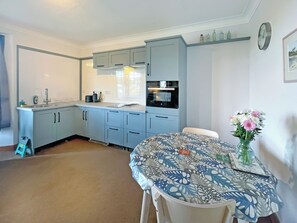 Une cuisine compacte avec des meubles de couleur bleu clair, un évier et un coin repas avec une table mise pour deux personnes.